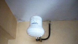 A white ceiling light fixture with a black cord, mounted on a beige wall. - Kwiremia Hotel (Embu)