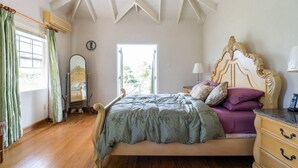 Un dormitorio con cama, cómoda, espejo y ventana con cortinas.