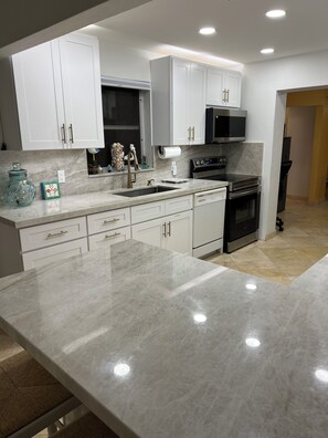 A modern kitchen with white cabinetry, a stainless steel range, and a built-in oven. - Hollywood Oasis (Hollywood)