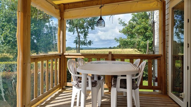 A wooden deck with a covered seating area, overlooking a natural landscape. - Normandy: nature, history and comfort in a mobile home (Litteau)