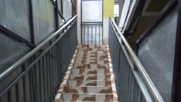 Una escalera con baldosas estampadas y barandillas de metal.