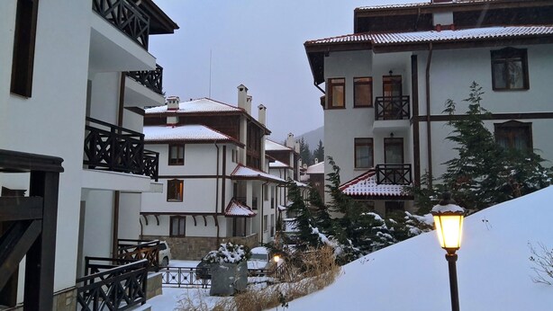 A snow-covered residential street with multi-story buildings, balconies, and a street lamp. - Apartment for rent in the Rhodope mountain suitable for all year long (Smolyan)