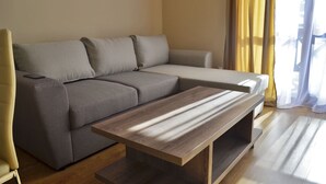 A modern living room with a grey sofa, a wooden coffee table, and a yellow armchair. - Apartment for rent in the Rhodope mountain suitable for all year long (Smolyan)