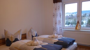 A double bed with a view of a snowy landscape through a window. - Cable car, lift, slopes, ski schools are within walking distance. Family friendly (Kurort Oberwiesenthal)