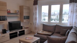 A living room with a TV, sofa, and a table with magazines. - Cable car, lift, slopes, ski schools are within walking distance. Family friendly (Kurort Oberwiesenthal)