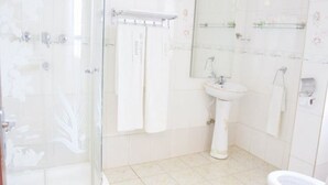 A bathroom with a glass shower enclosure, a pedestal sink, and a toilet.