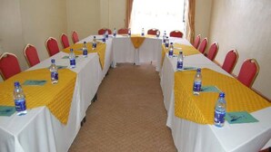 A conference room with long tables, red chairs, and yellow tablecloths.