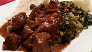 A plate of food with meat, greens, and a side of white rice.