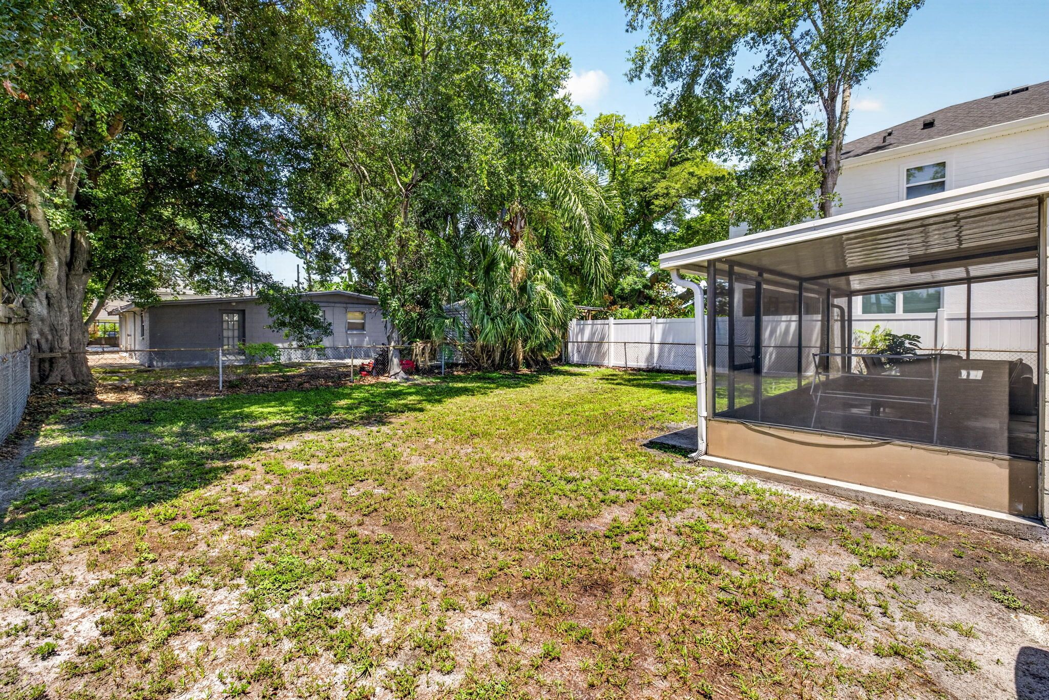 A residential area with a grassy yard, a covered outdoor seating area, and a house with a garage.