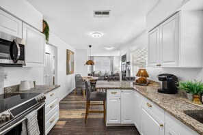 A modern kitchen with white cabinets, a granite countertop, and a central island with seating.