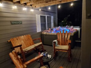 Eine Holzterrasse mit zwei Schaukelstühlen und einem Whirlpool.