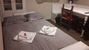 Un dormitorio con una cama, una silla, un escritorio y una pared de piedra.
