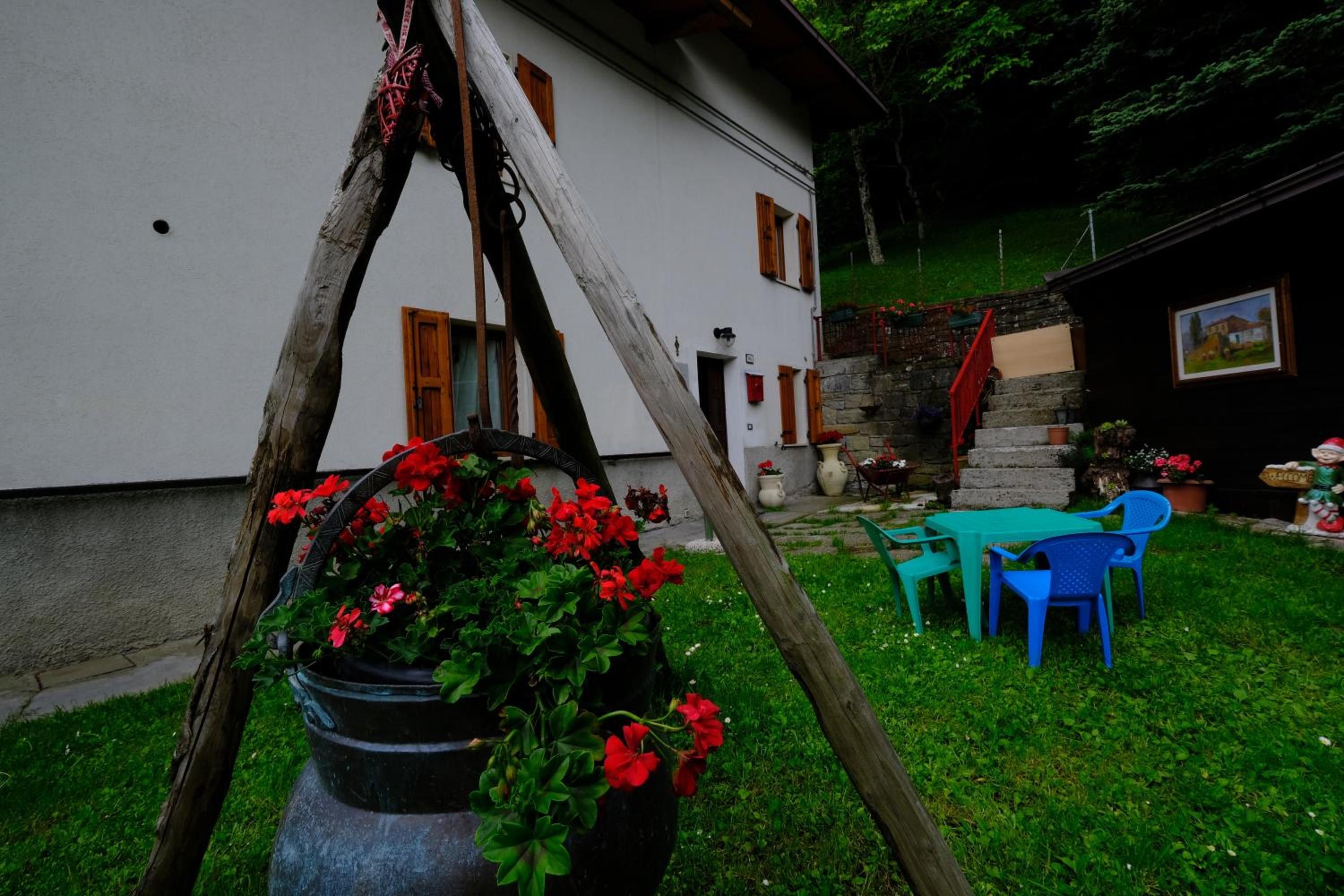 Un edificio bianco con un muro in pietra, una porta in legno e un piccolo giardino con tavolo e sedie.