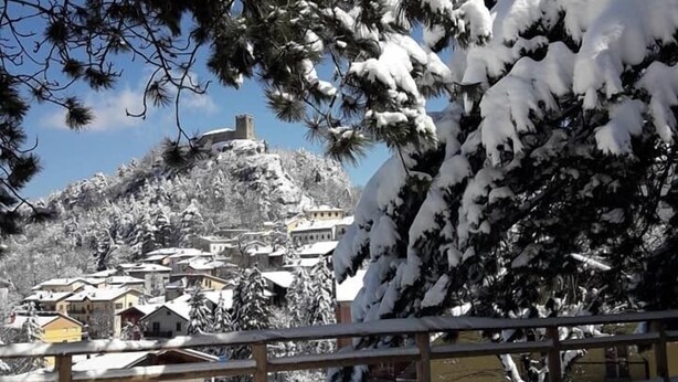 Un pueblo cubierto de nieve con edificios tradicionales y una iglesia destacada en una colina.