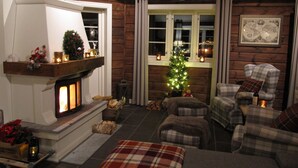 Un salon chaleureux avec une cheminée, des meubles à motifs écossais et un sapin de Noël.