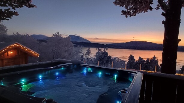 Un bain à remous avec vue sur un lac et des montagnes, au crépuscule.
