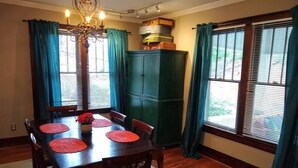 A dining room with a wooden table, chairs, and a chandelier. There are curtains on the windows, and a green cabinet is visible. - 2 blocks to North Chattanooga revitalized riverfront restaurants and bars. (Chattanooga)