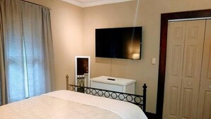A hotel room with a bed, a television mounted on the wall, a small white bedside table, and a wardrobe. - 2 blocks to North Chattanooga revitalized riverfront restaurants and bars. (Chattanooga)