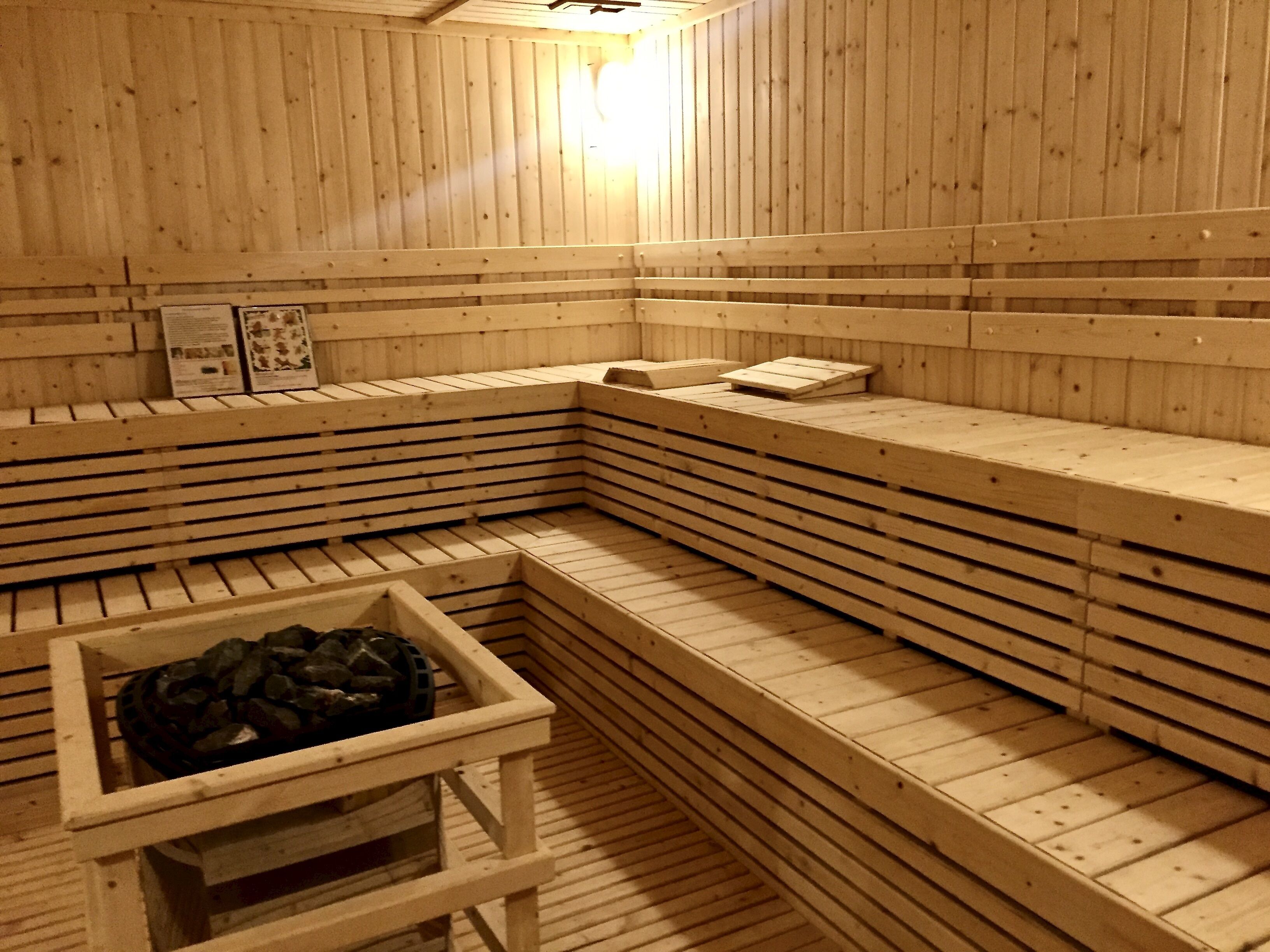 A wooden sauna with benches and a stone basin.
