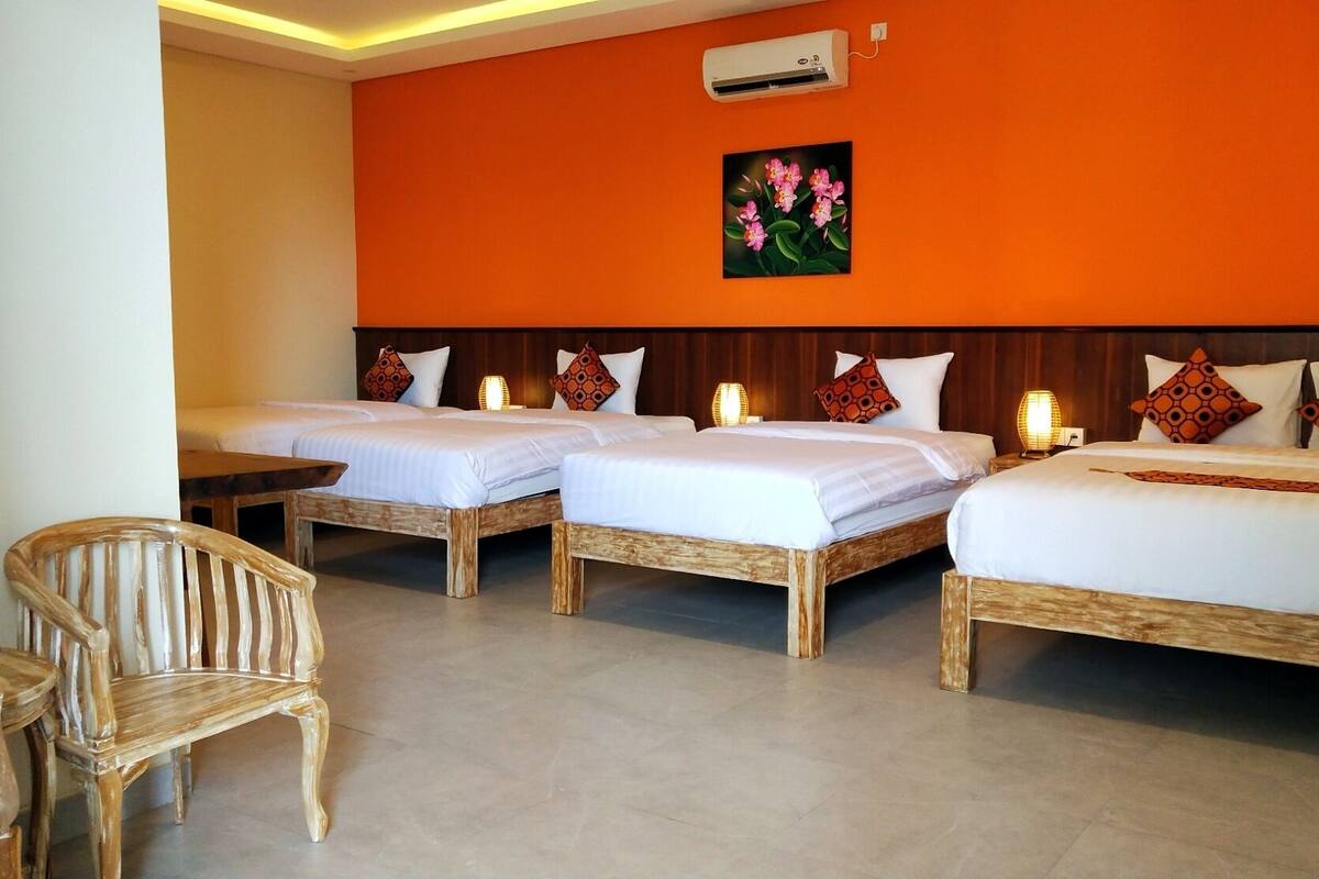 Een hotelkamer met twee eenpersoonsbedden, een tweepersoonsbed, een houten stoel en een kleine tafel.