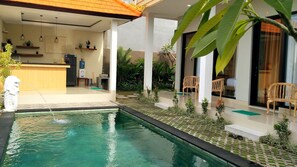 A pool area with a water feature, a wooden bench, and a seating area with a view of the pool. - Umah Dangin Guesthouse - Hostel (Munggu)