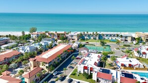 Um resort costeiro com vários edifícios, piscina e praia ao fundo.