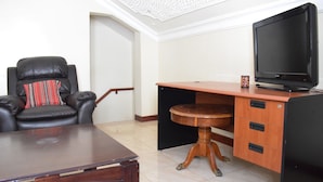 Una habitación con un escritorio de madera, una silla de cuero, un televisor y una pequeña mesa.