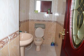 A bathroom with a toilet, sink, and a window above the toilet. - Bustani Apartment (Mombasa)