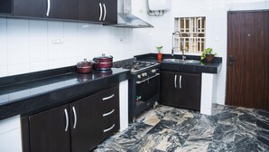 A modern kitchen with dark cabinets, a stove, and a sink. - Lineech Apartments (Abuja)