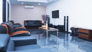 A modern waiting area with leather sofas, a coffee table, and a flat-screen TV mounted on the wall. - Lineech Apartments (Abuja)
