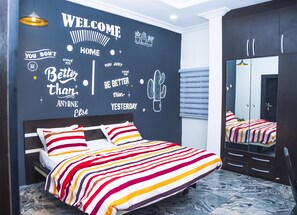 A modern bedroom with a bed, a mirror, and motivational wall art. - Lineech Apartments (Abuja)
