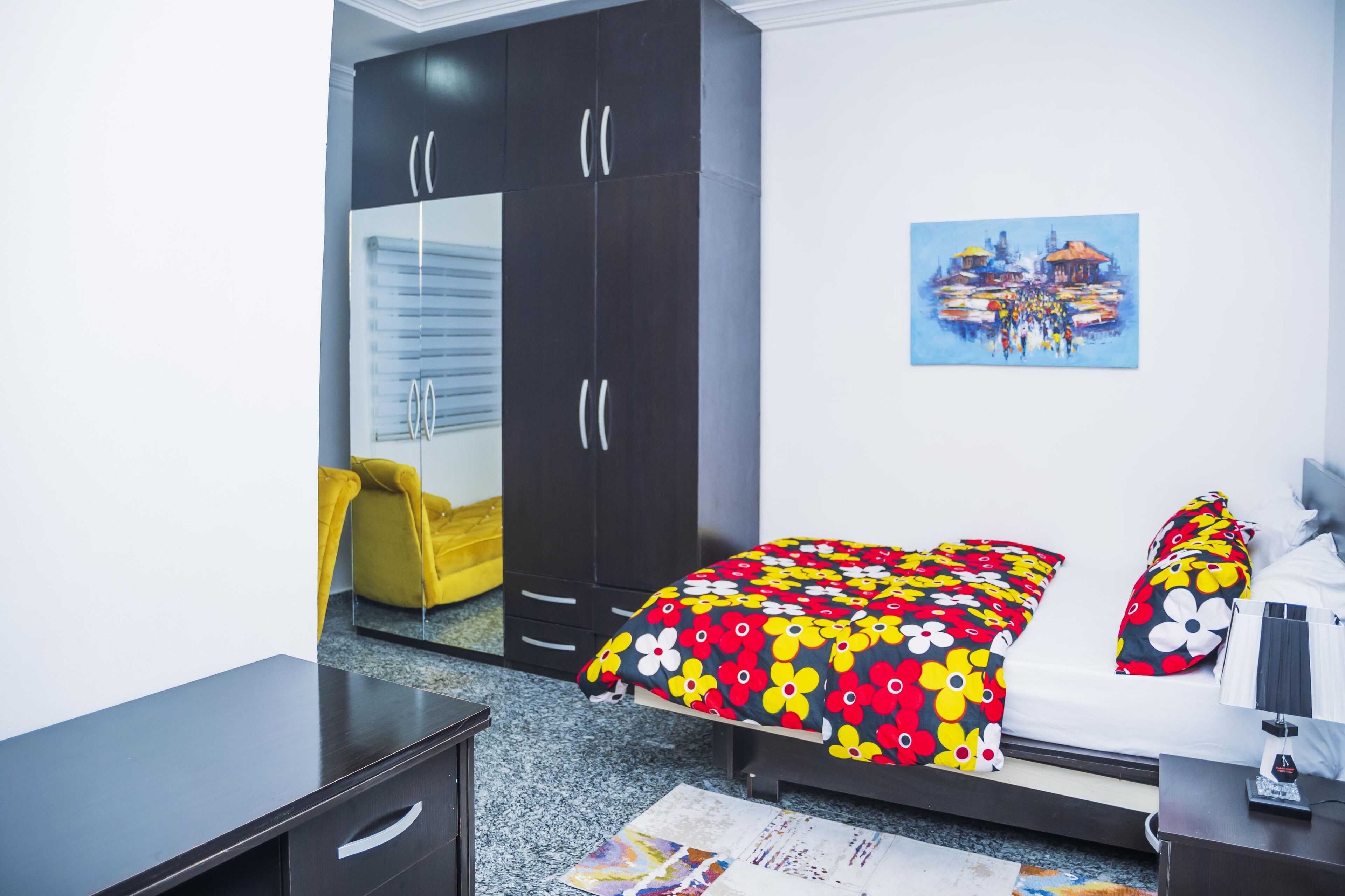 A bedroom with a bed, a wardrobe, a desk, and a chair.