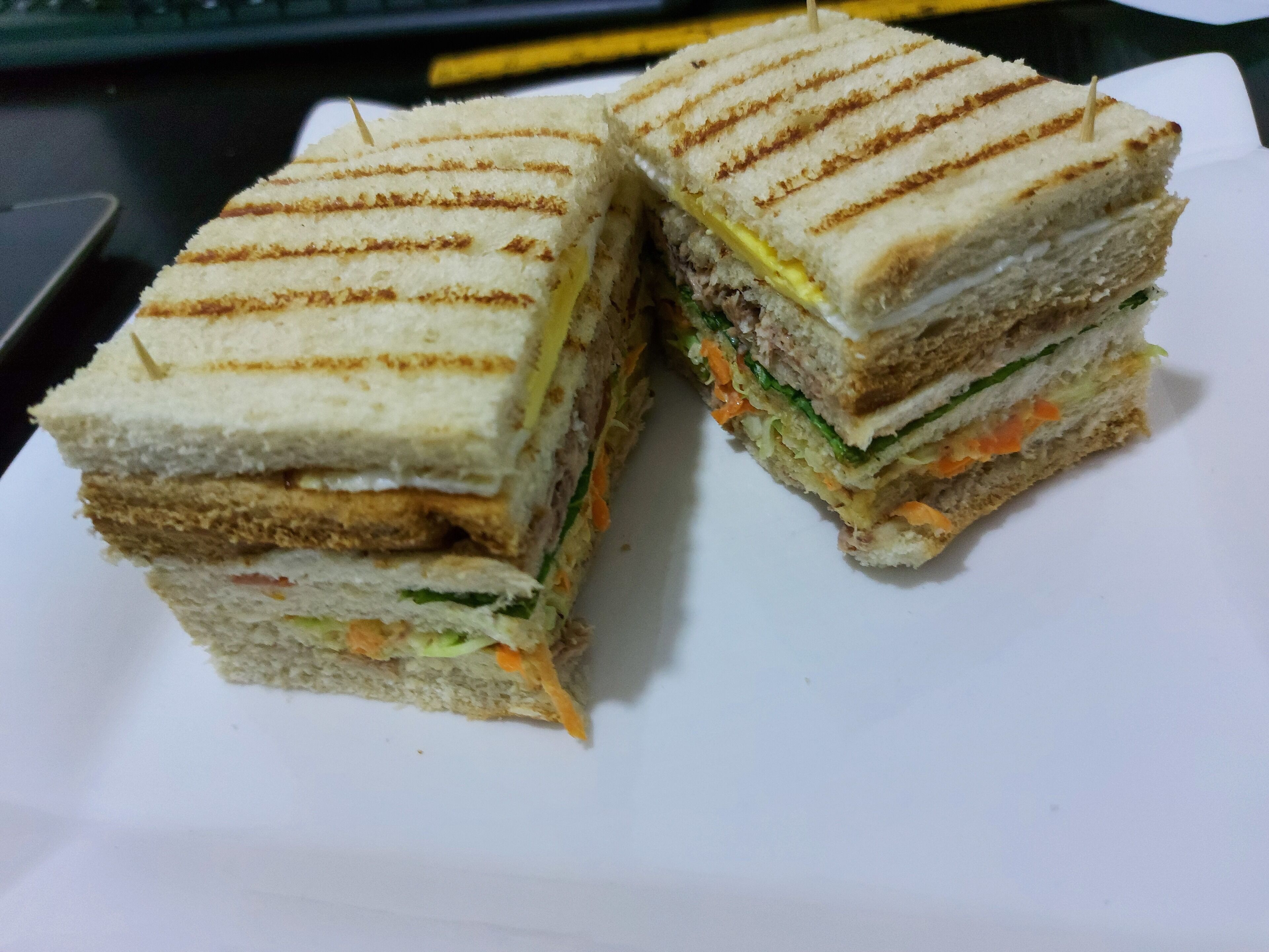 Een belegd broodje, doormidden gesneden, met zichtbare lagen brood, sla en andere vulling.