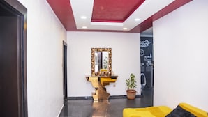 A modern lobby with a yellow sofa, a unique gold and black mirror, and a red ceiling. - Lineech Apartments (Abuja)