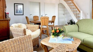 A cozy living area with wicker furniture, a wooden table with a vase of flowers, and a green sofa.