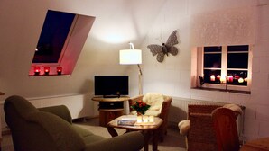 A cozy living room with a television, a table with candles, and a butterfly wall decoration.