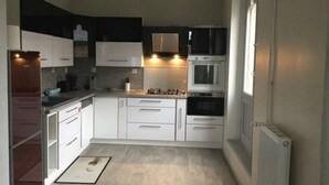 A modern kitchen with white cabinets, a built-in oven, and a gas stove.