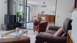 Ein modernes Wohnzimmer mit Flachbildfernseher, Ledersofas und einem Glastisch.