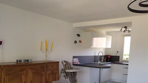 Eine moderne Küche mit weißen Schränken, einer eingebauten Spüle und einem Essbereich mit Stuhl und Tisch.