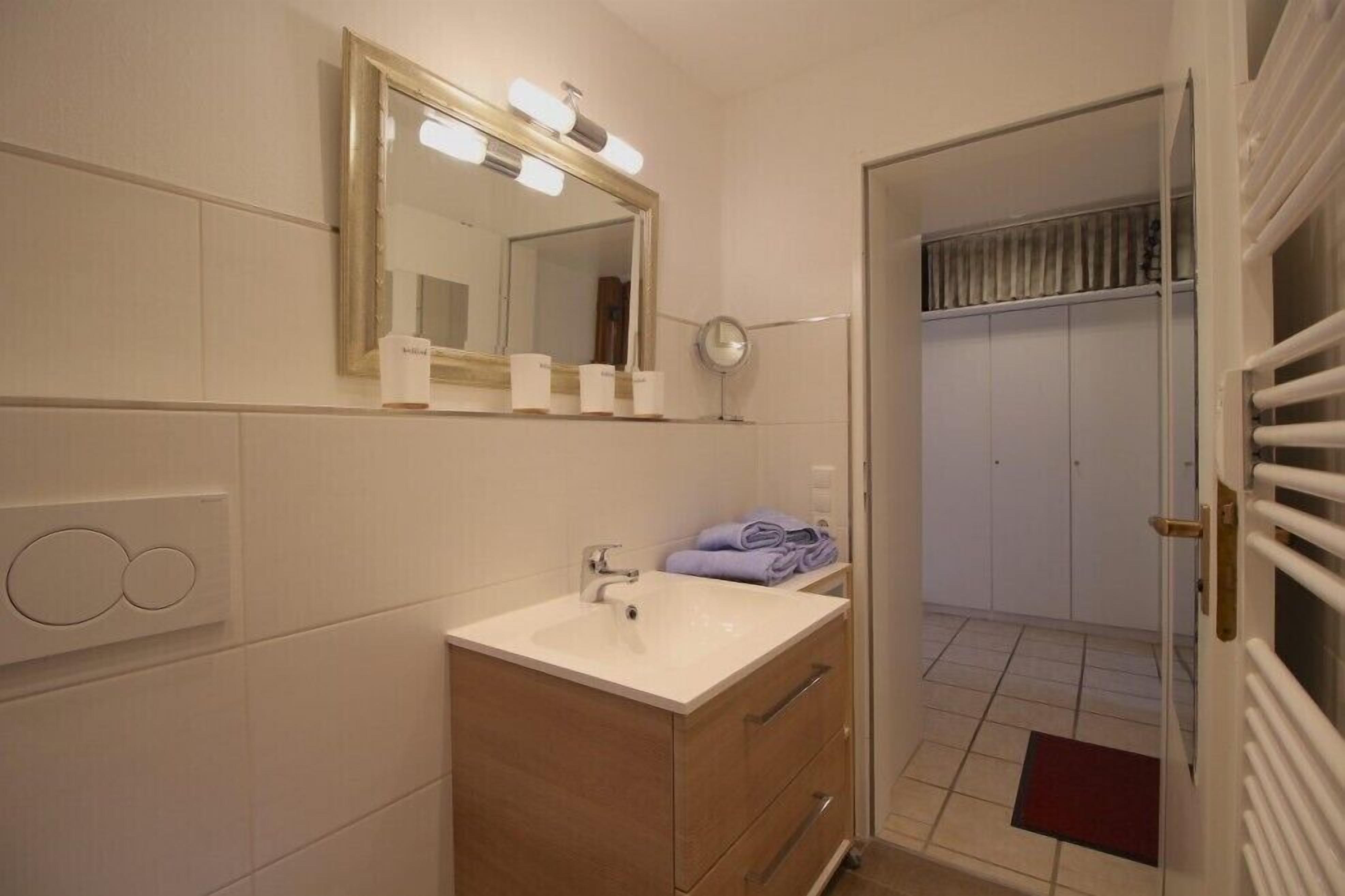 Une salle de bain équipée d’un lavabo, d’un miroir et d’un porte-serviettes.