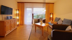 A living room with a sofa, a television, a wooden cabinet, and a table. - Farchanter Alm (Farchant)