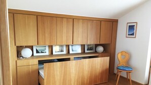 A compact room with wooden cabinetry, a bed, and a chair. - Marie-Anne (Garmisch-Partenkirchen)