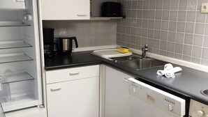 A kitchen with white cabinets, a black countertop, a coffee maker, and a dishwasher. - Marie-Anne (Garmisch-Partenkirchen)