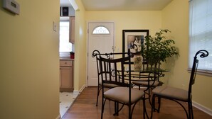 A dining area with a round table and chairs, a potted plant, and a door with a glass window. - SWEET! near Downtown PWR & LIGHT Westport KUMC (Kansas City)