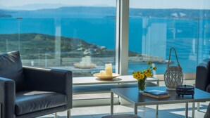 Une chambre moderne avec vue sur la mer, un canapé, une table agrémentée de bougies et de fleurs, et une lanterne décorative.