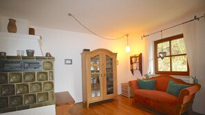 A cozy living room with a wooden cabinet, a red sofa, and a window with curtains. - Chalet Adriana (Garmisch-Partenkirchen)