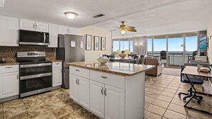 A modern kitchen with built-in appliances, a dining area with a view, and a balcony with a view. - 1011 Waters Edge Resort 2 Bedroom Condo by RedAwning (Murrells Inlet)