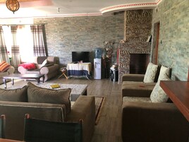Una sala de estar con una pared de piedra, una chimenea y un televisor.