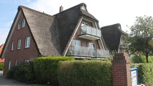 Ein Haus mit einem steilen Satteldach, einer Ziegelaußenwand und einem Balkon mit Metallgeländer.