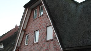 Ein Gebäude aus roten Ziegelsteinen mit einem steilen Satteldach und einer kleinen Veranda.